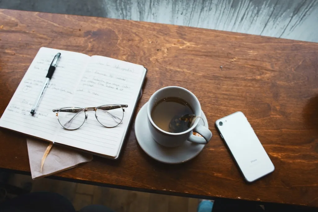 working desk with a notebook, tea and a phone