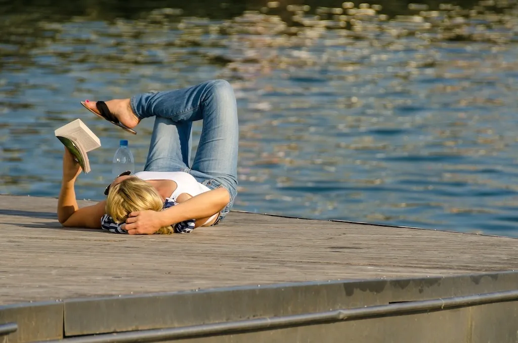 woman reading a book by the lake