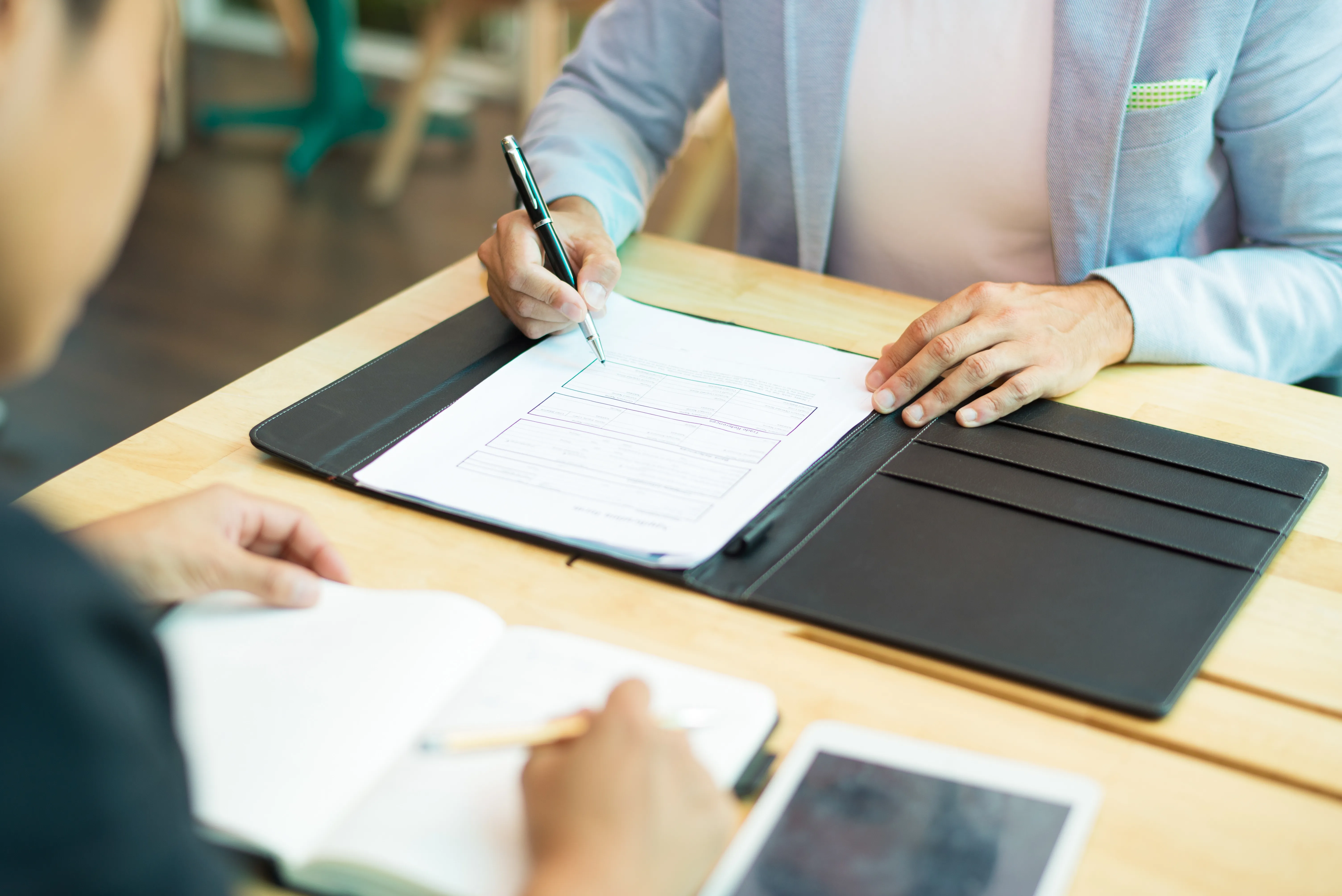 close-up-businessman-sitting-table-filling-document.webp