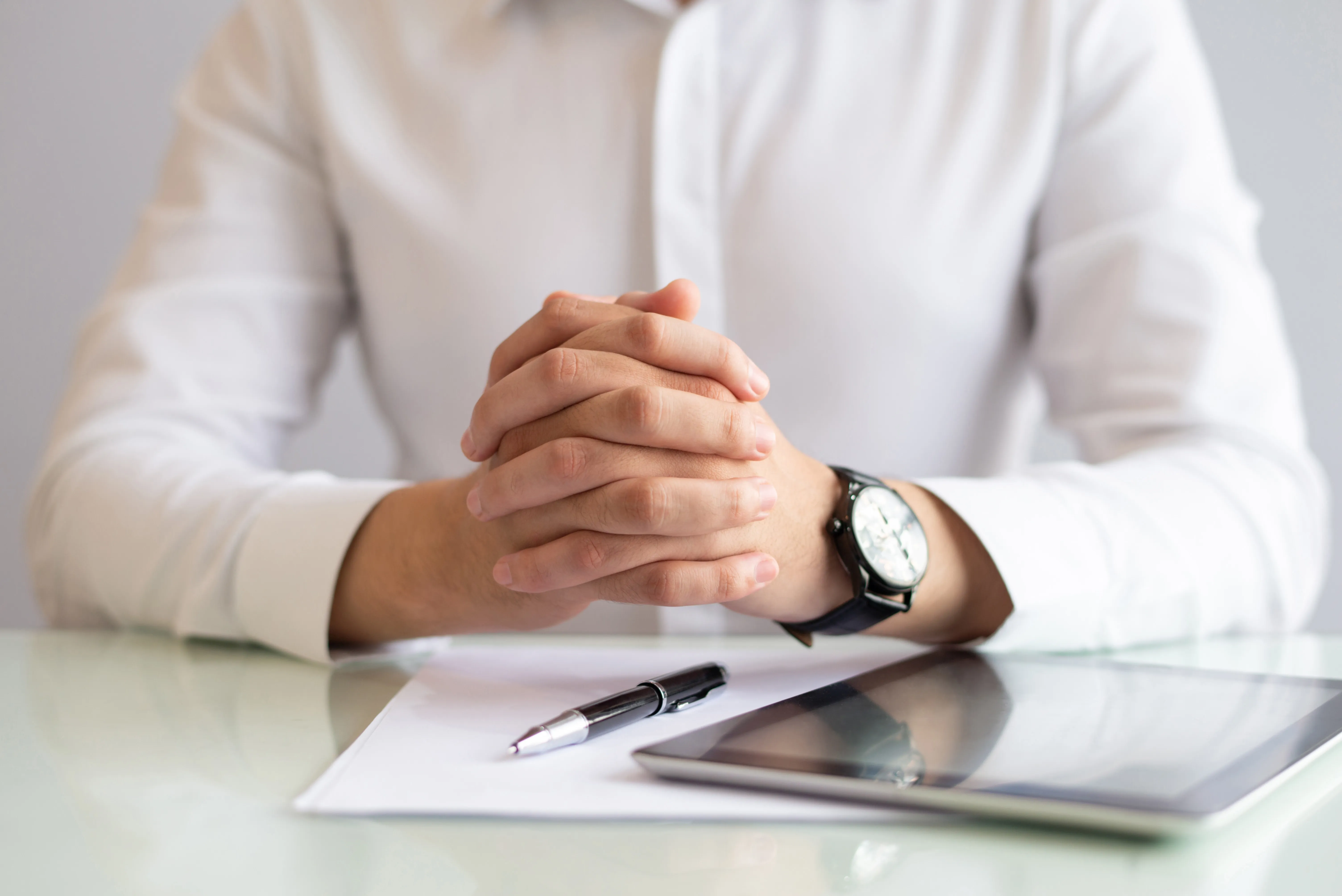 close-up-male-executive-sitting-table-with-clasped-hands.webp