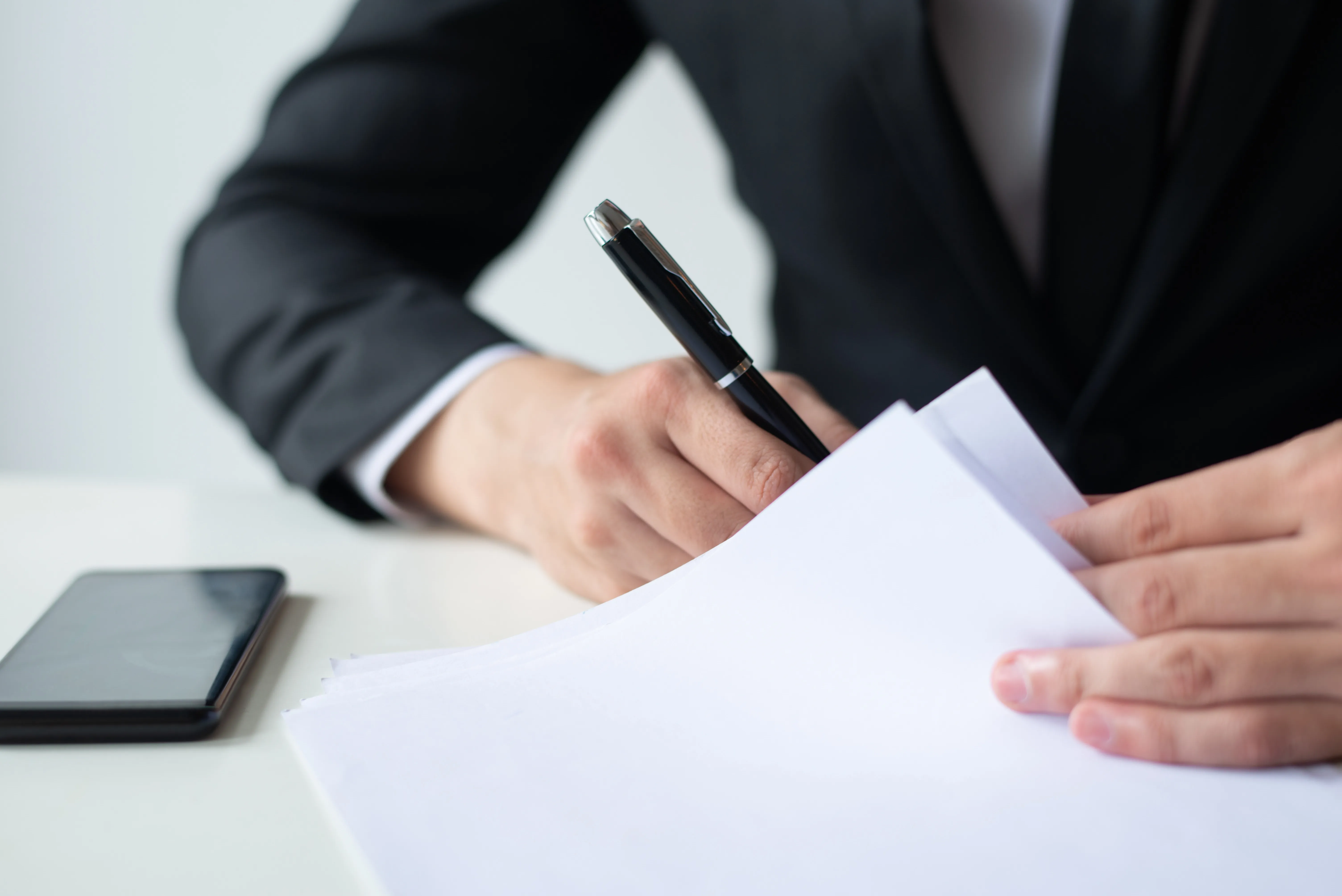 closeup-business-man-signing-document-office-desk.webp