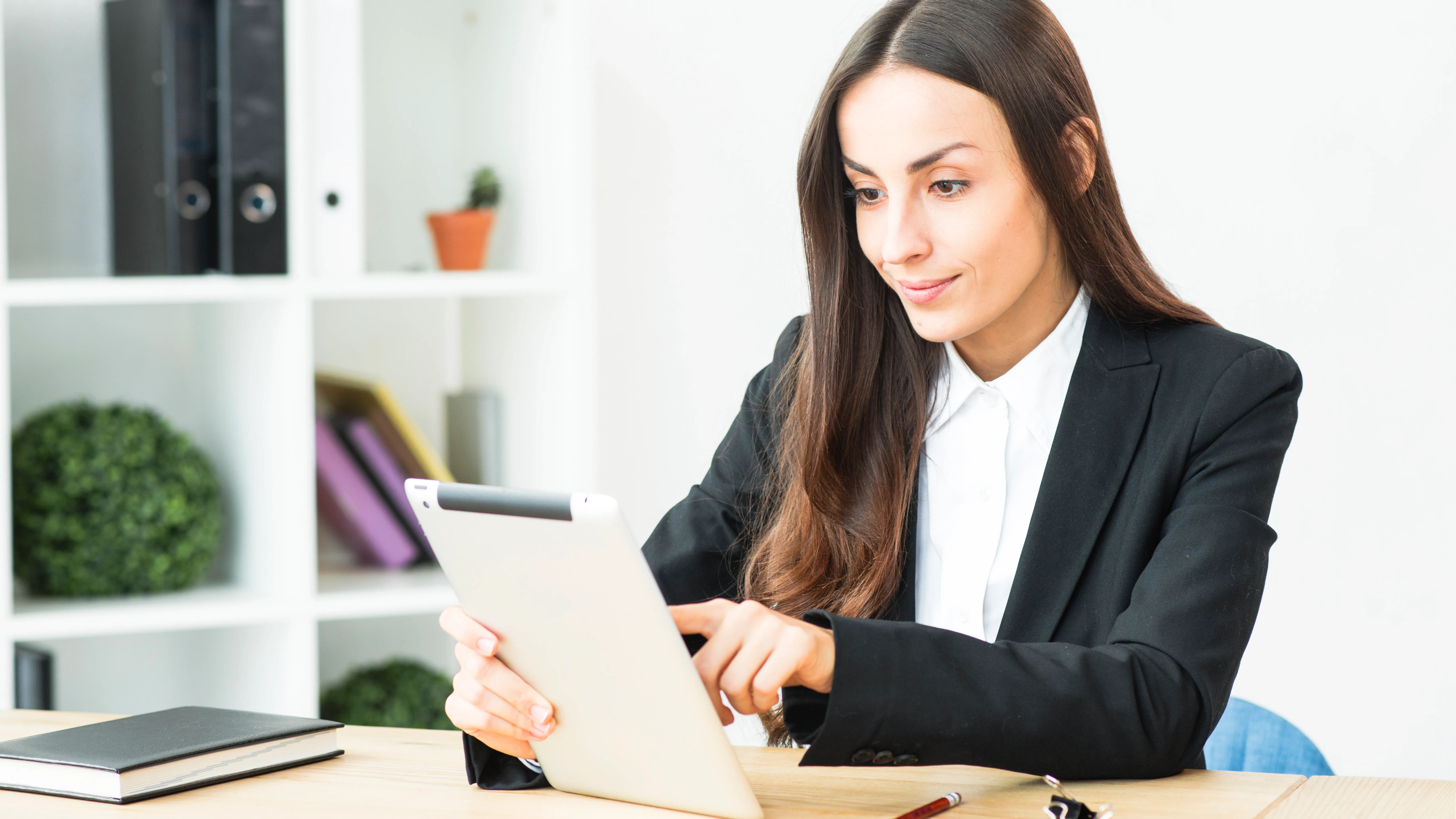 smiling-young-businesswoman-touching-digital-tablet-sitting-office-desk.webp